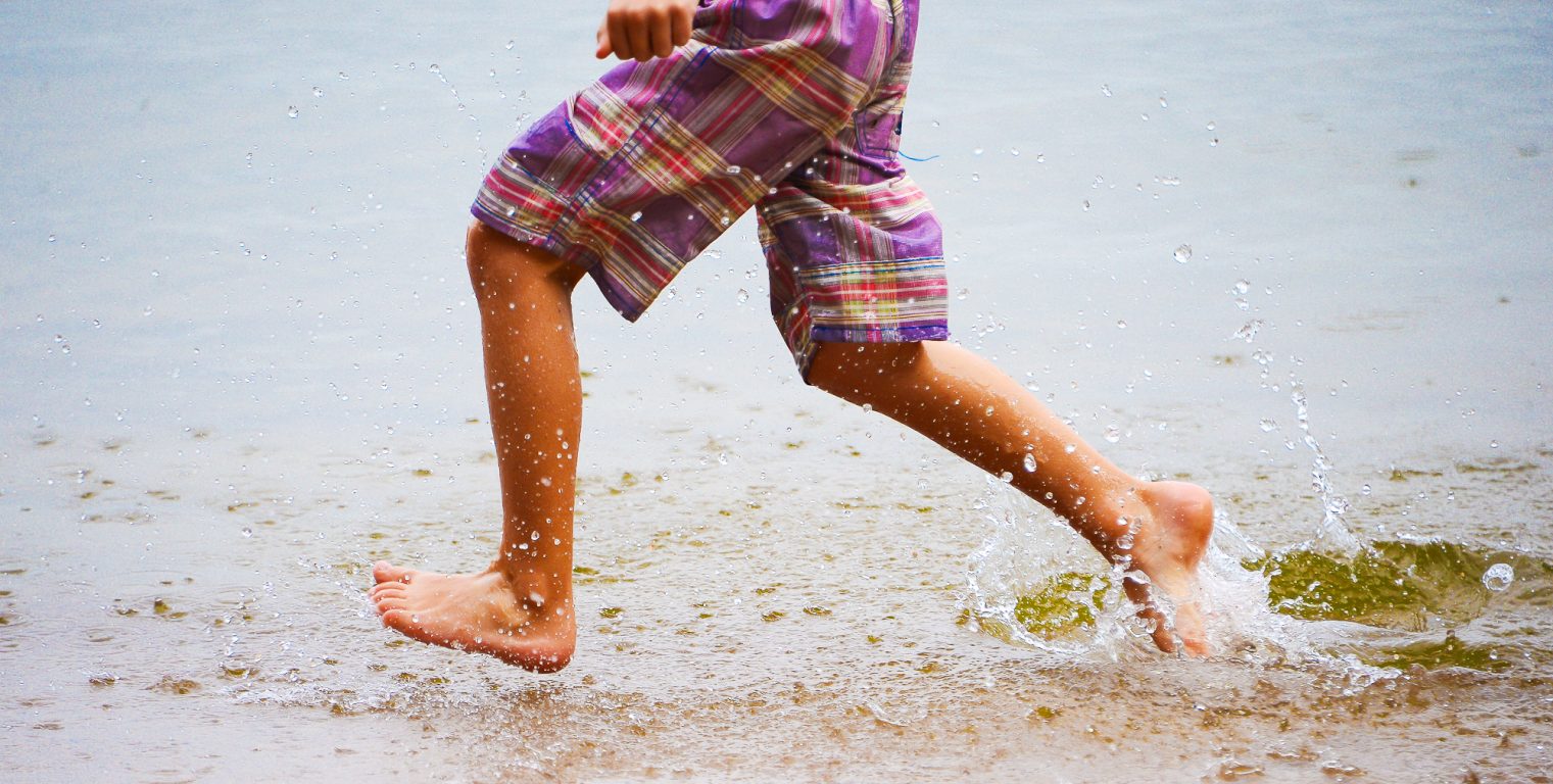 Barns fötter som springer i havet