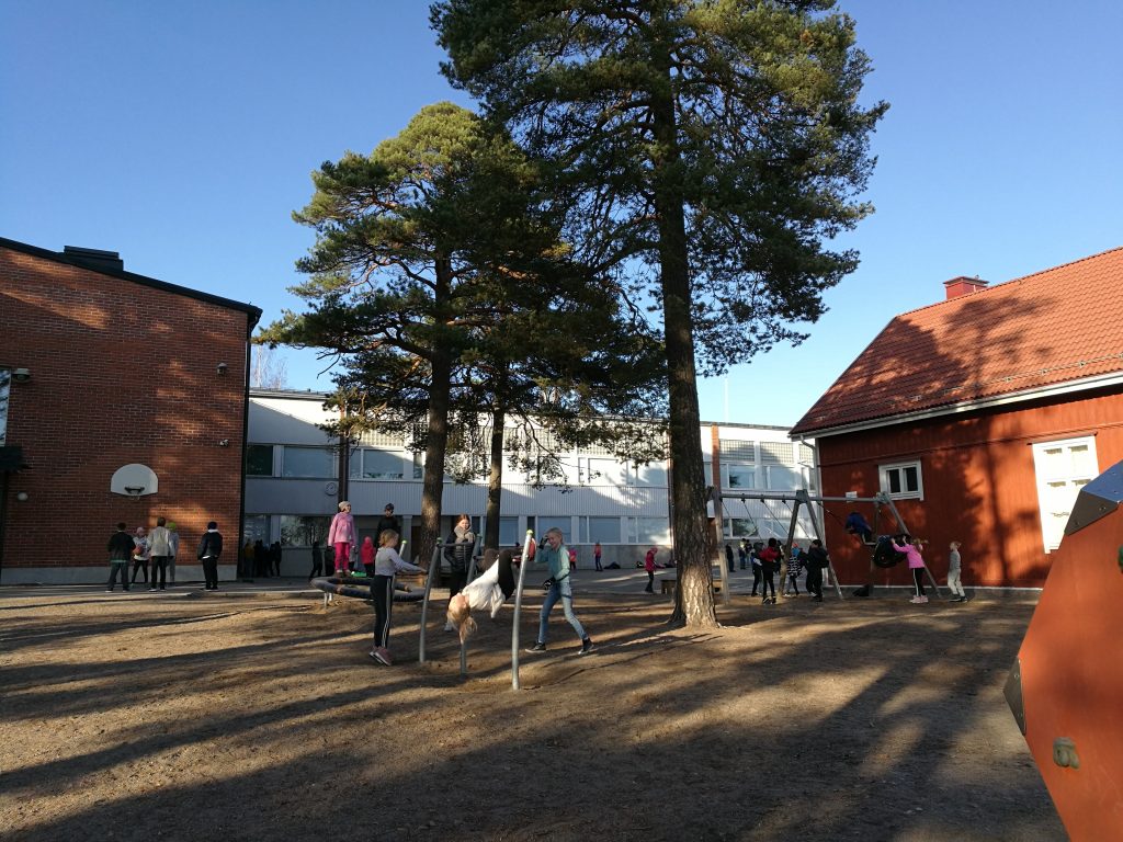 Kiilan koulun pihanäkymä ja oppilaita käyttämässä liikuntavälineitä